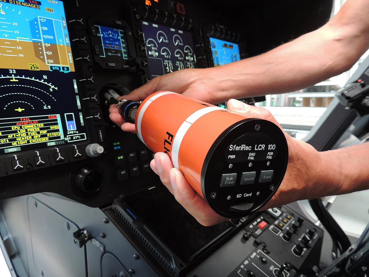 [Translate to English:] Nahaufnahme zweier Hände, die einen Light Weight Flight Recorder im Cockpit einbauen.