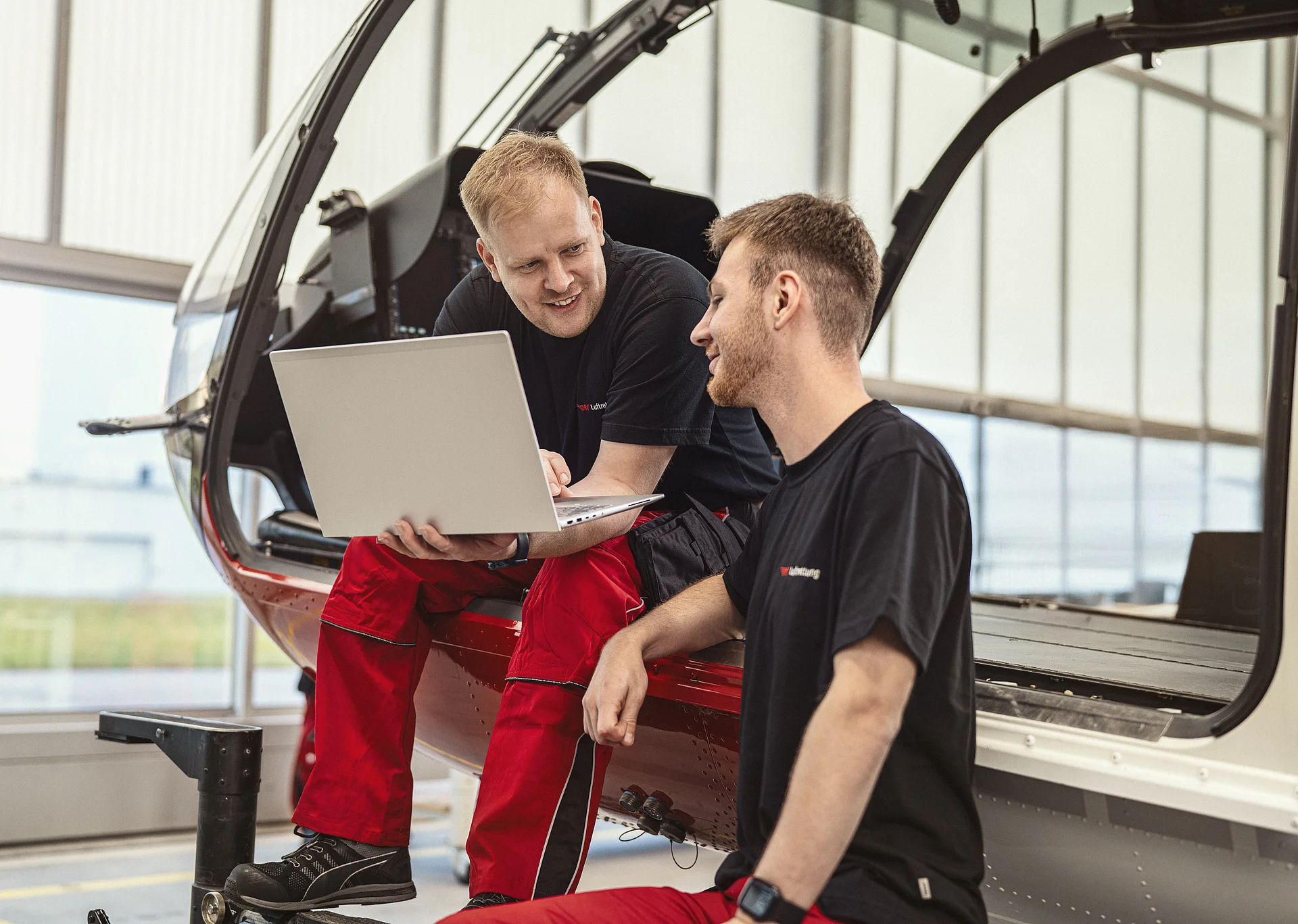 Zwei Techniker der DRF Luftrettung unterhalten sich und schauen dabei auf einen Laptop.